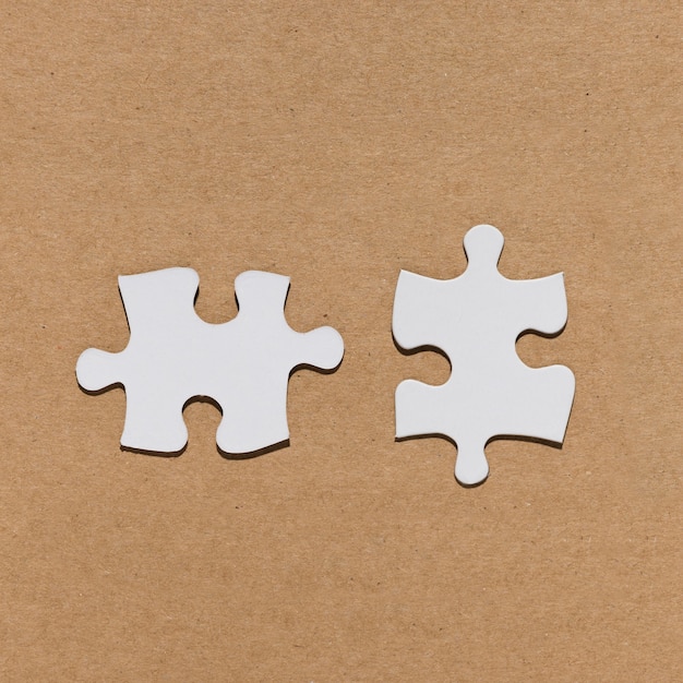 White jigsaw puzzle piece over brown paper textured backdrop