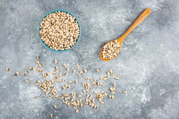 White kidney beans in blue bowl with wooden spoon.