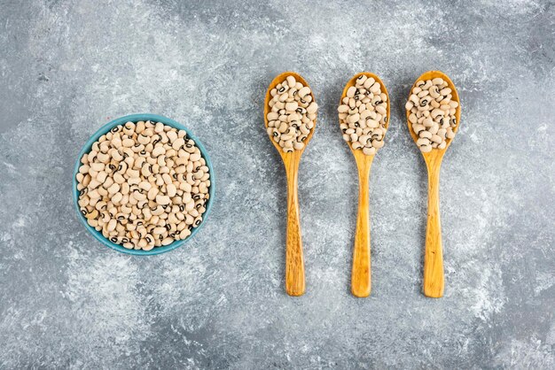 White kidney beans in blue bowl and wooden spoons.