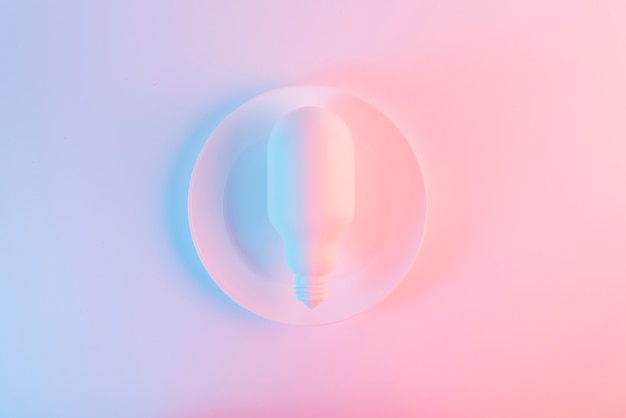 Free photo white light bulb on plate against blue and pink background