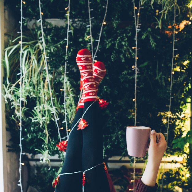 White light garlands twine around legs in red socks