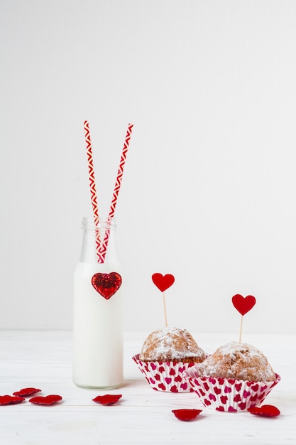 White liquid in bottle with tubes near cakes with heart on wands