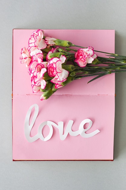 Free photo white love inscription with flowers on notebook