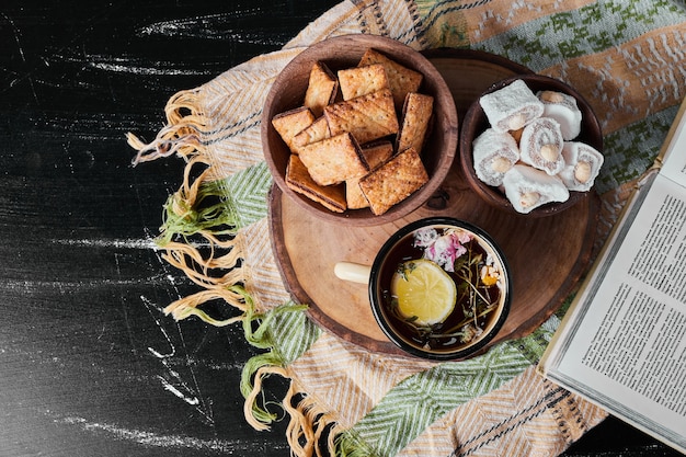 White marshmallows in a metallic cup with herbal tea and crackers.