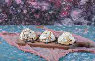 Free photo white meringue cookies with black raisines on a wooden board.