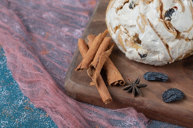 White meringue cookies with black raisines on a wooden board.