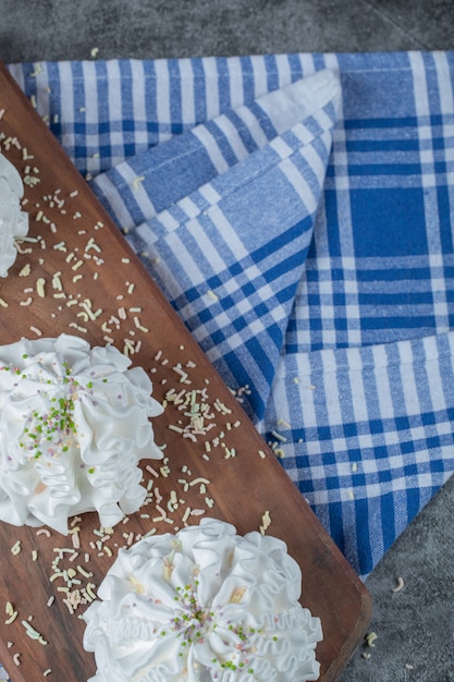 Free photo white meringue cookies with coconut powder on a wooden board on the blue towel.