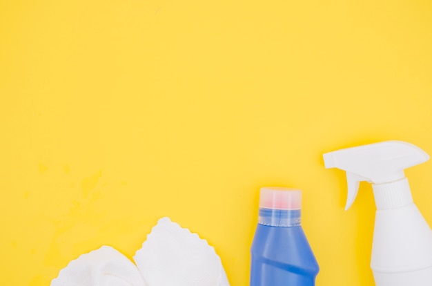 Free photo white napkin; spray bottle and detergent blue bottle with copy space for writing the text on yellow backdrop