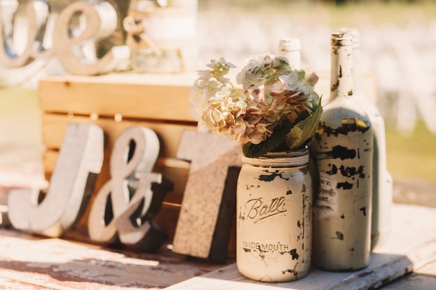 Free photo white old bottles with beige flowers stand before wooden