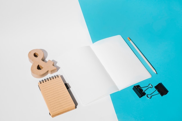 White page; bulldog clips; pencil; ampersand symbol and spiral notepad on dual backdrop