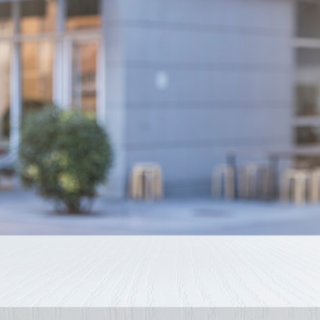 Free Photo white painted wooden table in front of office building