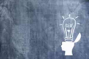 Free photo white paper cutout open head over the drawn ideas light bulb on blackboard