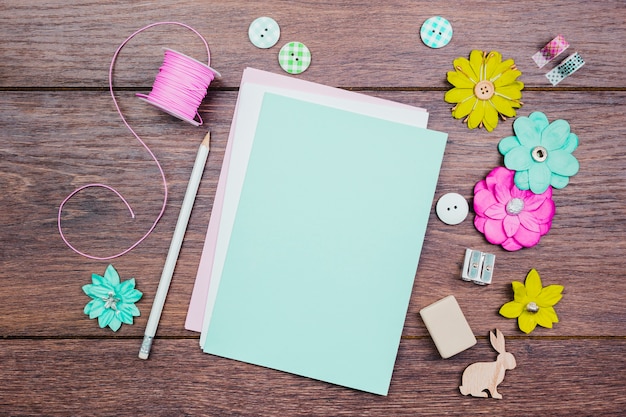 Free photo white pencils; buttons; colorful flowers and pink spool on wooden table