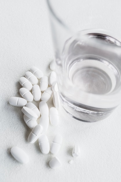 White pills near a glass of drinking water