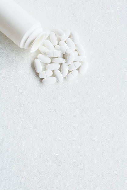 Free photo white pills and plastic bottle on white background