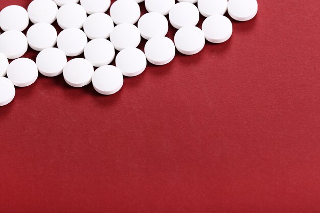 White pills on red surface