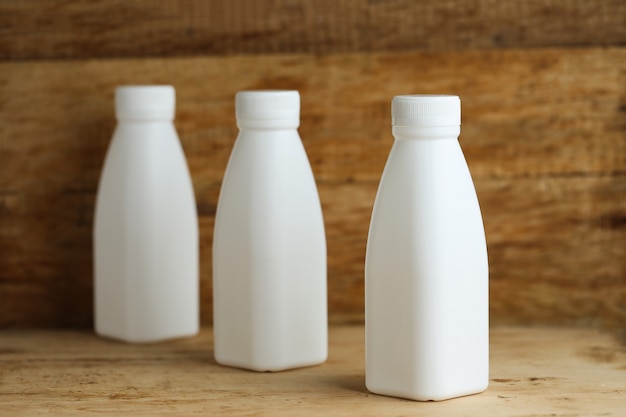 Free photo white plastic milk bottles on retro wooden table background