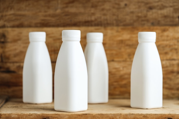 Free photo white plastic milk bottles on retro wooden table background