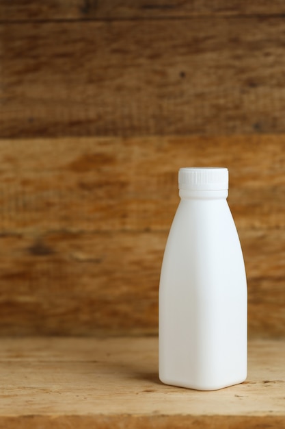 white plastic milk bottles on retro wooden table background