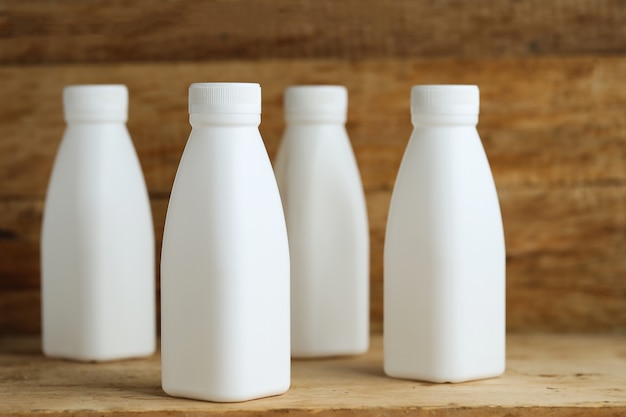 white plastic milk bottles on retro wooden table background