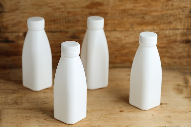 white plastic milk bottles on retro wooden table background