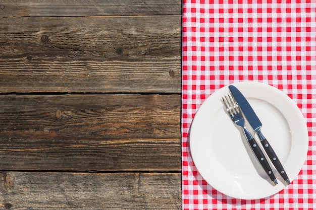 Free Photo white plate on checkered table cloth and wooden textured plank