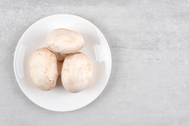 White plate of fresh big mushrooms on stone table. 