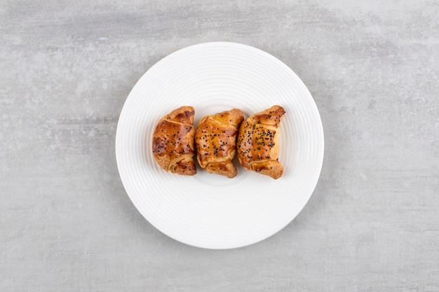 White plate of fresh tasty pastries on stone table. 