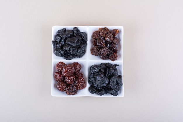 Free Photo white plate full of dried tasty plums on white background. high quality photo