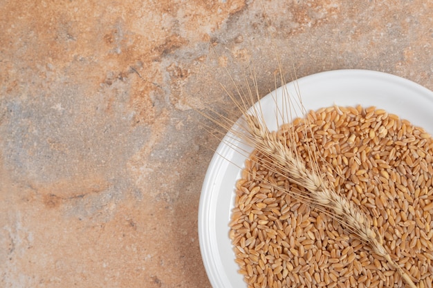 A white plate of grains and wheat on marble background. High quality photo