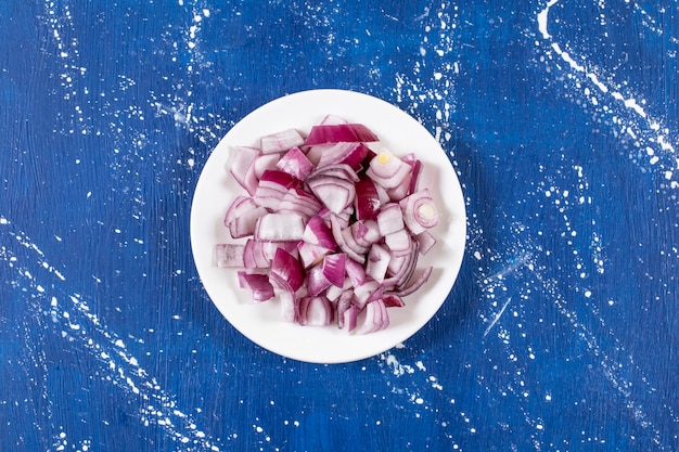 Free photo white plate of sliced purple onions on marble surface