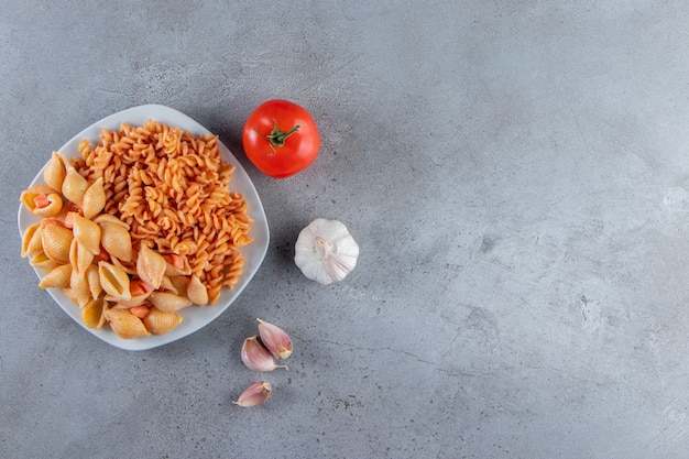 Free Photo white plate of two various creamy pasta on stone background. 