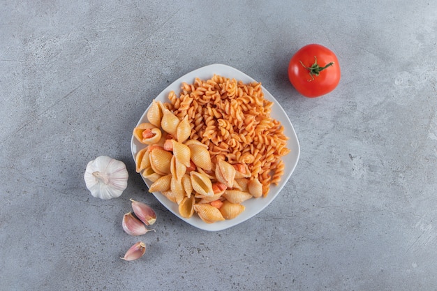 Free photo white plate of two various creamy pasta on stone background.