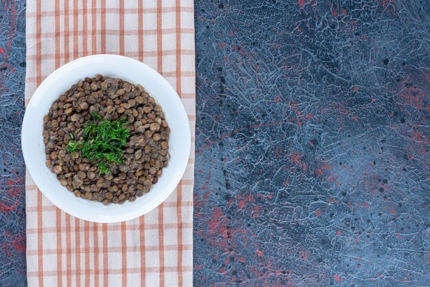 Free photo a white plate with beans and herbs on a tablecloth