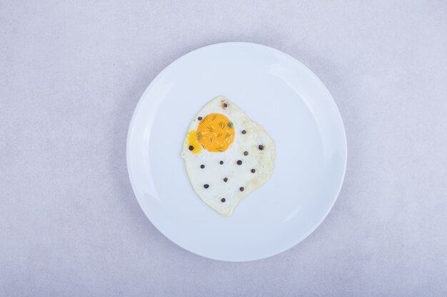 A white plate with omelet, pepper .