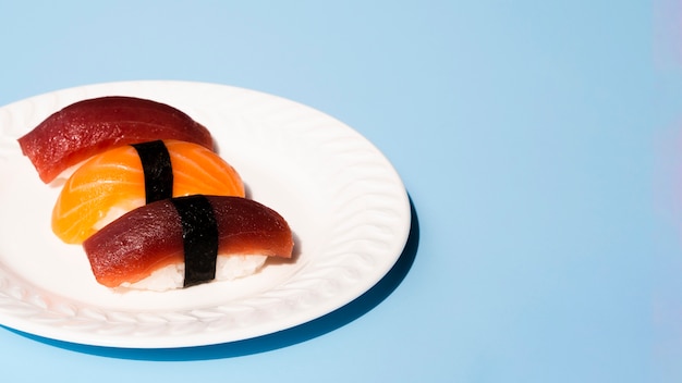 Free photo white plate with tuna and salmon sushi on a blue background