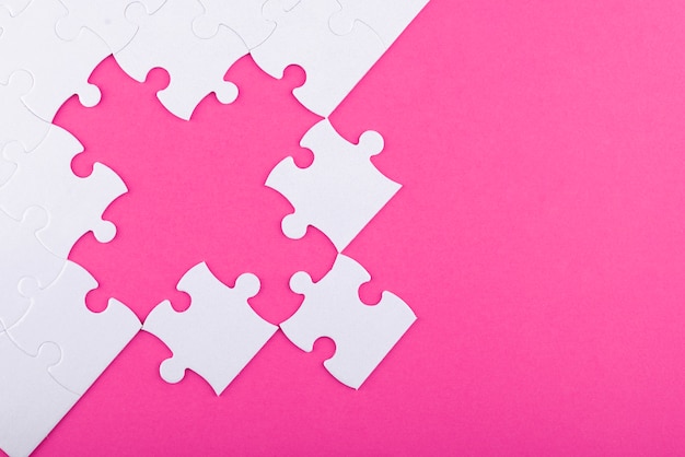 Free photo white puzzle pieces and pink background