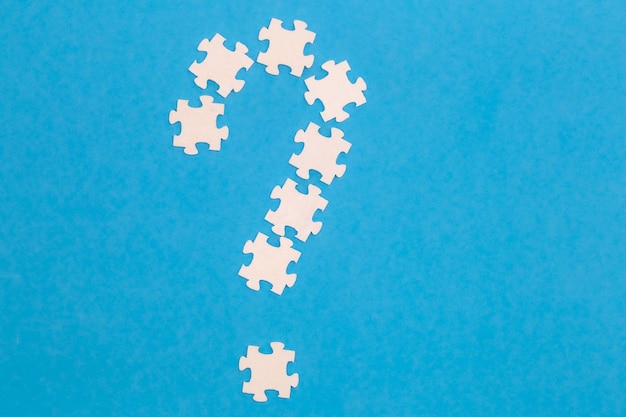 Free Photo white puzzles in the shape of a question mark on a blue background flat lay