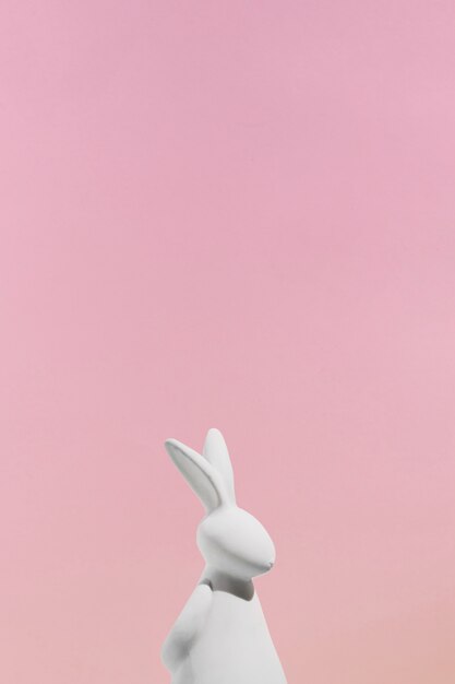 White rabbit figurine on pink background 