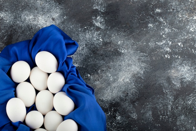 Free photo white raw chicken eggs with on a blue tablecloth .