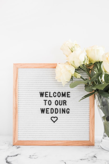 White roses flowers in vase and welcome board for wedding