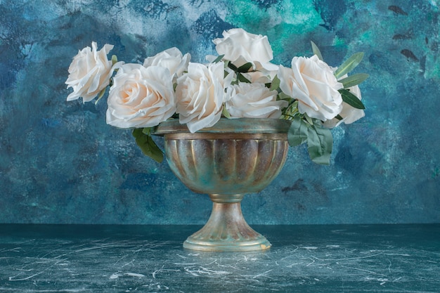 White roses in a iron bowl , on the blue background.