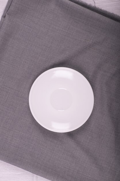 The white saucer with grey tablecloth