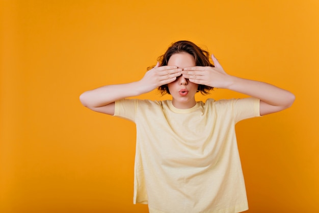 Free Photo white short-haired girl wears ring plays in hide and seek. indoor photo of brunette lady in oversize t-shirt covering eyes.