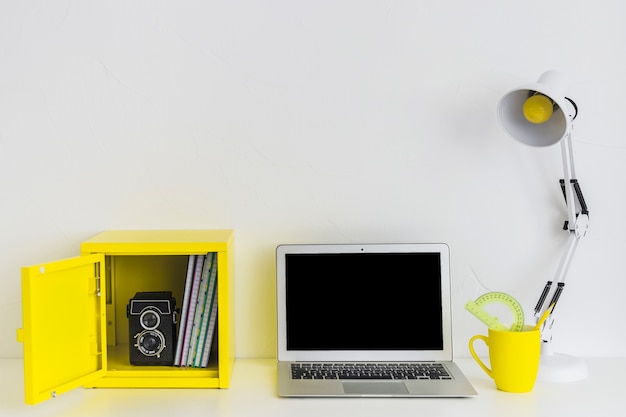 White stylish workplace in white and yellow colors with laptop and yellow box