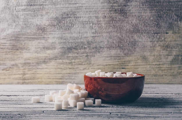 Free Photo white sugar cubes in a bowl on a white wooden table. side view.