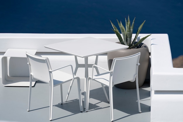 Free Photo white table and chairs on terrace in oia, santorini.