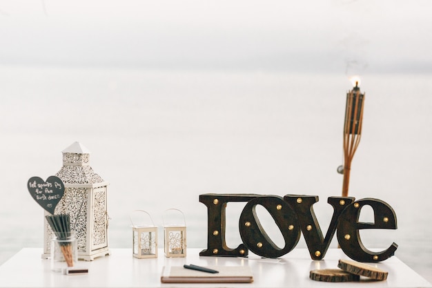 Free photo white table with decorative lanterns and steel lettering love