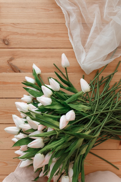 Free photo white tulips on natural wooden background topview. spring melody