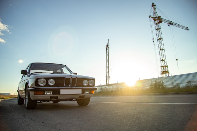 White vintage classic car with round headlights on the road during sunset